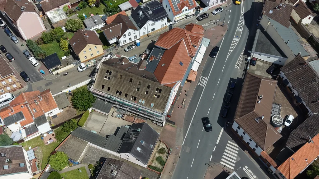 Luftbild einer Ortsdurchfahrt mit Baustelle an einem Mehrfamilienhaus